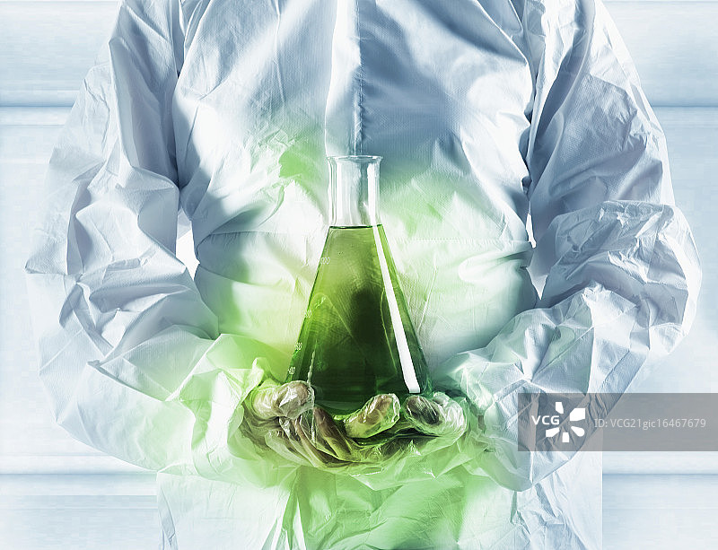 科学家拿着烧瓶中发光的绿色物质图片素材