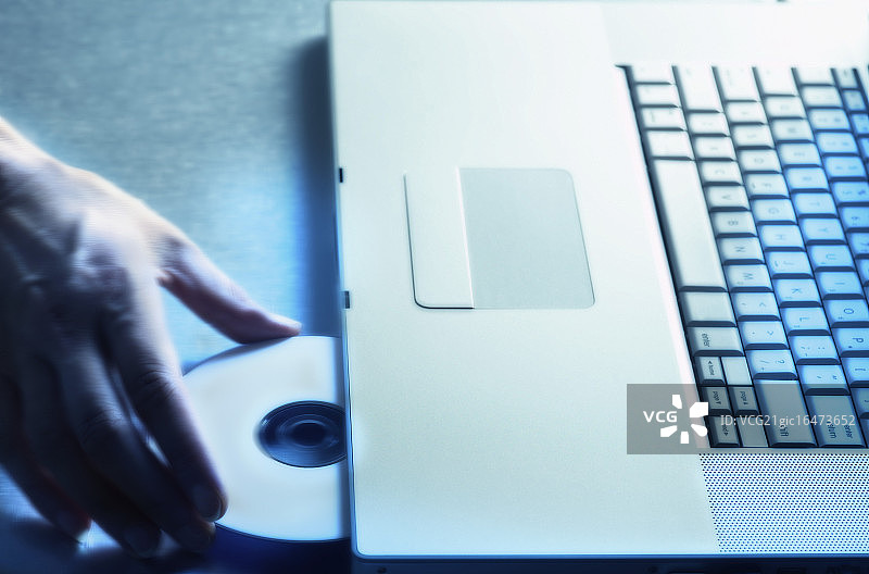 手将光盘放入笔记本电脑图片素材