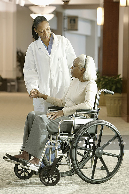 医生在坐在轮椅上的年长妇女旁边图片素材