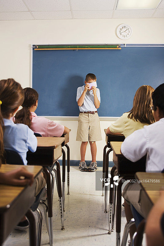 课堂展示中躲在笔记卡片后面的害羞学生图片素材