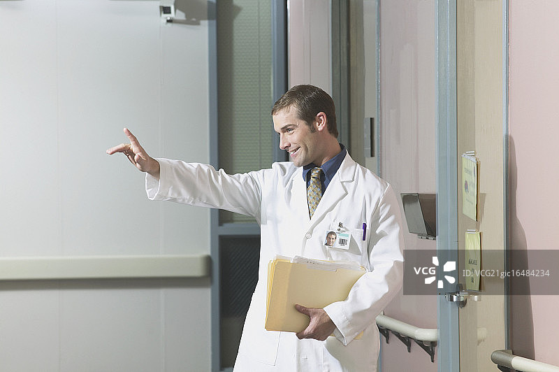 手拿文件夹敬礼的年轻男医生肖像图片素材