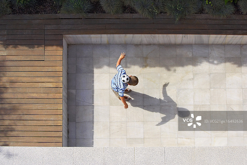 男孩在院子里踢足球图片素材