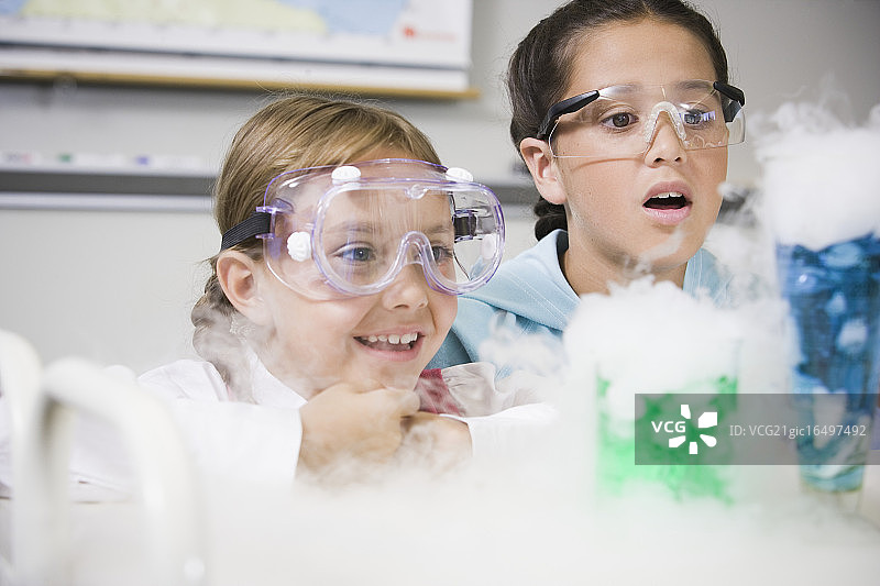 女孩们观看冒烟的化学实验图片素材