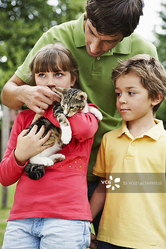 一家人抱着并爱抚他们的小猫图片素材