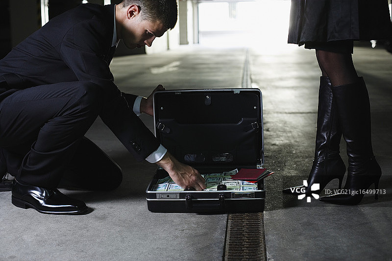 男人看着装满现金和文件的公文包图片素材