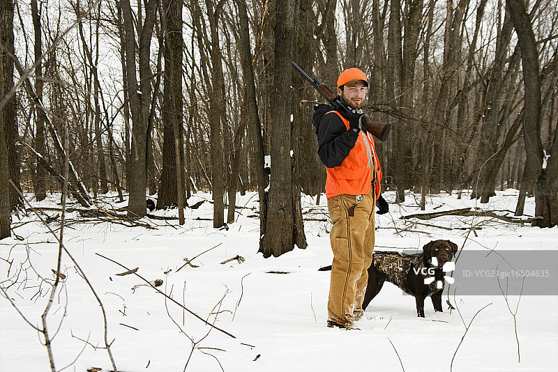 猎人和巧克力色拉布拉多犬在雪地里图片素材