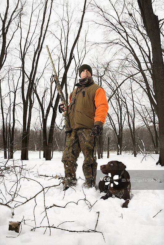 猎人和巧克力色拉布拉多犬在雪地里图片素材