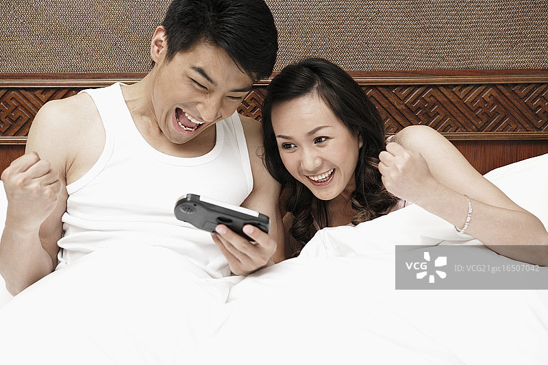 情侣在床上看便携式电视图片素材