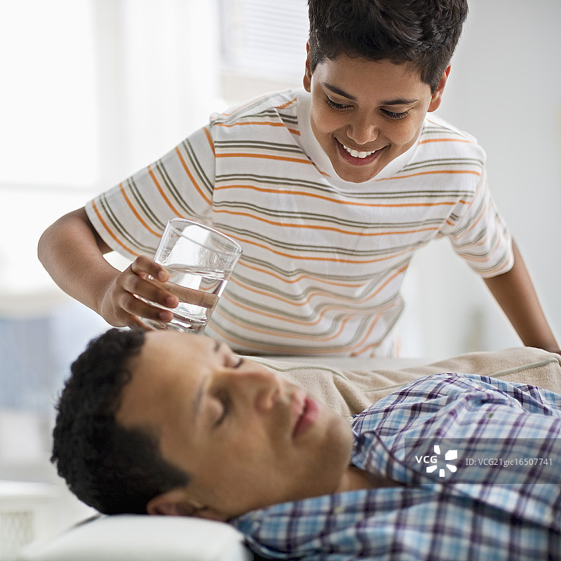 男孩往熟睡的父亲身上倒水图片素材