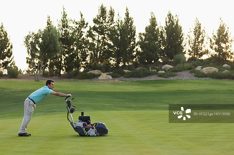 高尔夫球手推动高尔夫球场整理机图片素材