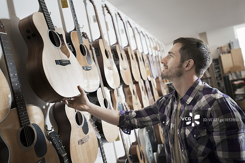 男人在商店选择吉他图片素材