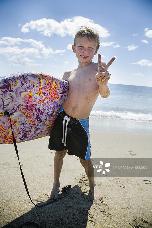 在海滩上携带趴板的男孩图片素材