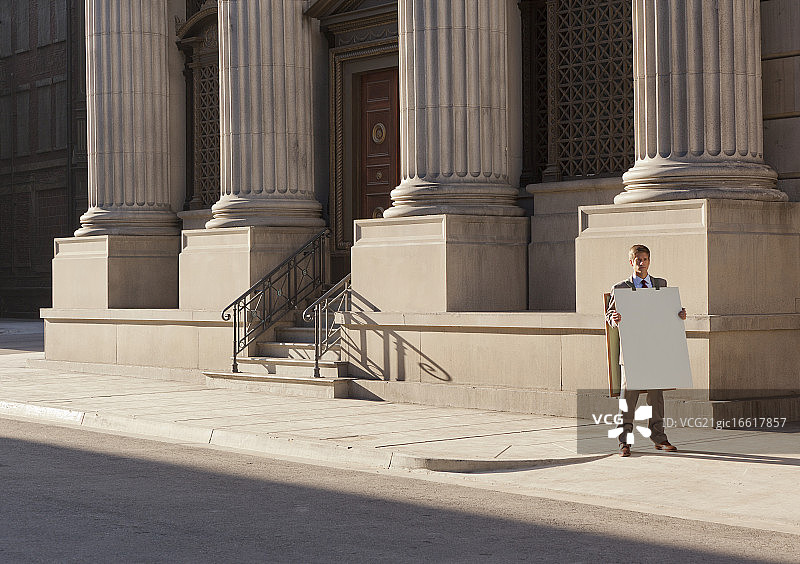 在人行道上穿着广告三明治板的男人图片素材