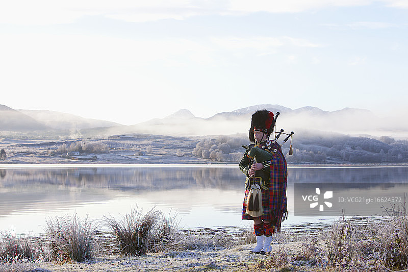 风笛手在苏格兰湖边吹奏风笛，苏格兰西海岸图片素材
