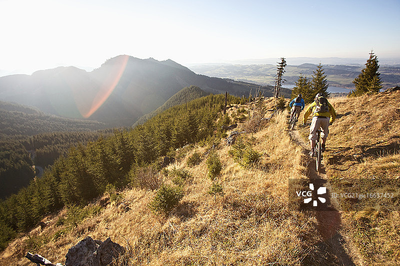 在德国加米施-帕滕基兴阿尔卑斯山小路上骑自行车的两人图片素材