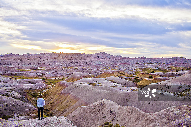 在美国南达科他州恶地国家公园观看日落的年轻男人图片素材