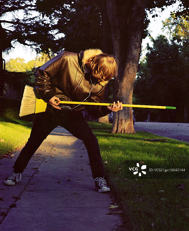 少年拿着扫帚弹奏空气吉他图片素材