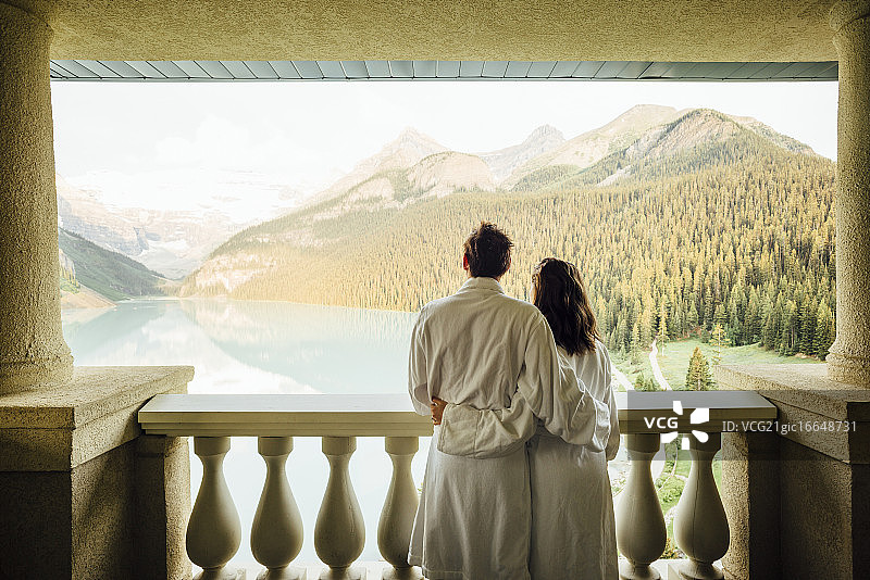 年轻夫妇在加拿大艾伯塔省班夫国家公园的路易斯湖阳台上眺望图片素材