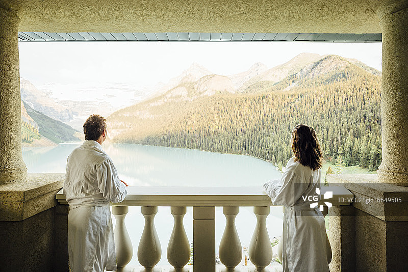 年轻夫妇在加拿大艾伯塔省班夫国家公园的路易斯湖阳台上眺望图片素材