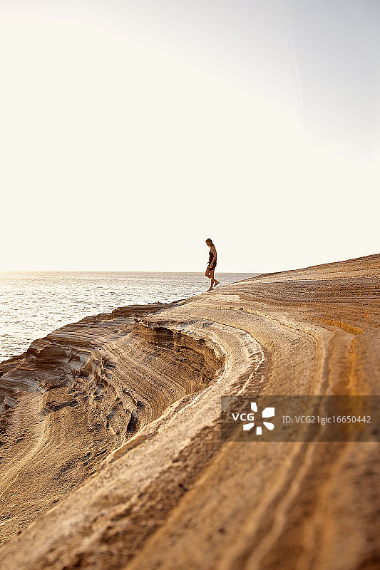 女人走在佛得角圣地亚哥岛普拉亚的岩石海岸上图片素材