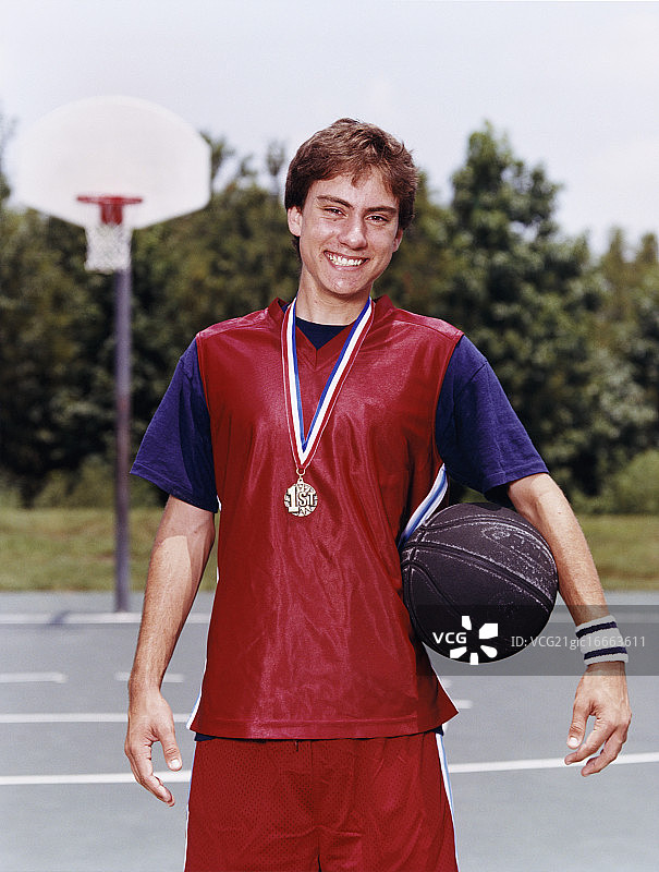 笑着手持篮球的青少年男孩与奖牌图片素材