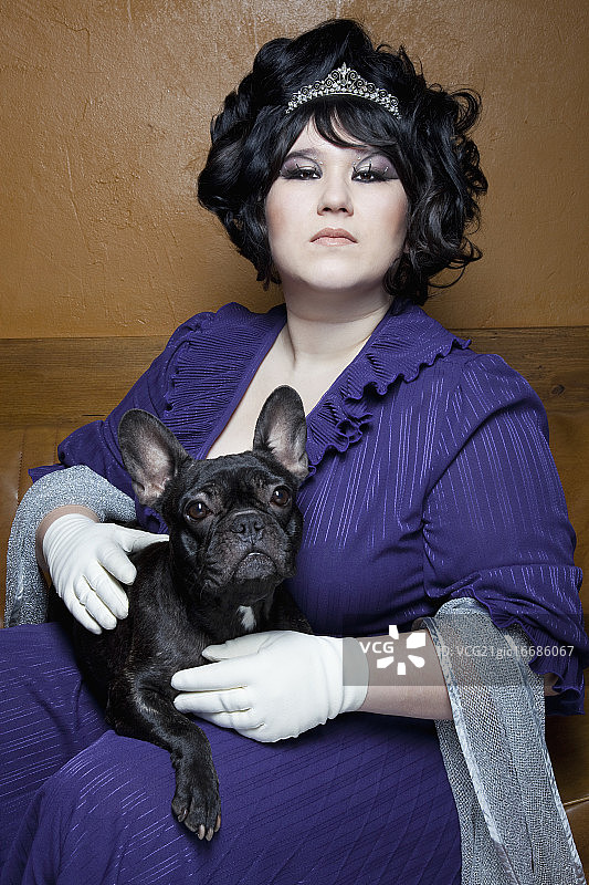 年轻女子盛装打扮，抱着法国斗牛犬。图片素材