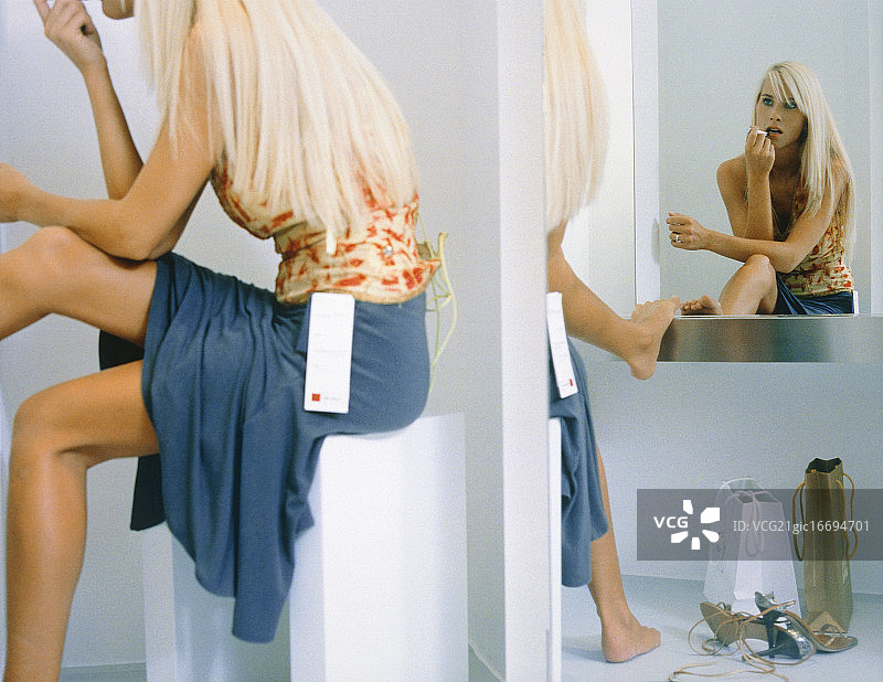 年轻女人在镜子前涂口红图片素材