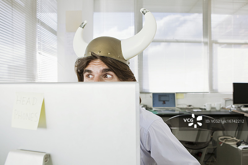 戴维京头盔的年轻商人从电脑屏幕后窥视图片素材