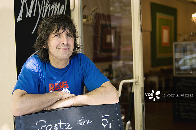 咖啡馆老板倚靠在广告牌上图片素材