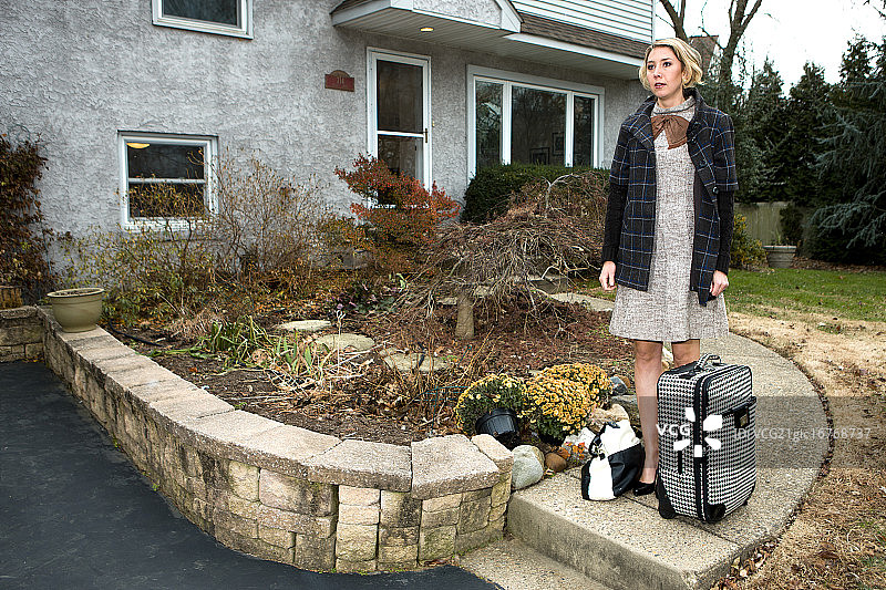 手提箱站在房子前的女人图片素材