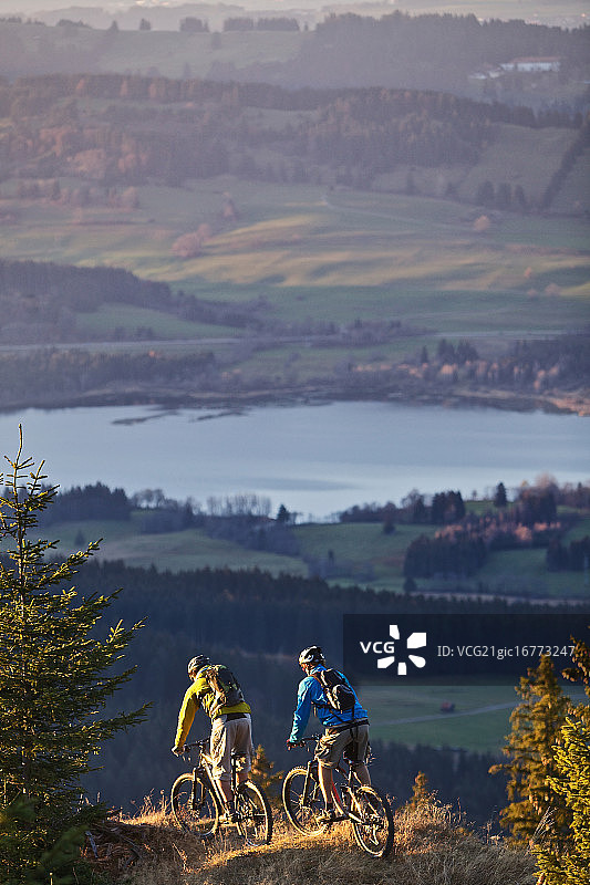 在德国加米施-帕滕基兴阿尔卑斯山小路上骑自行车的两人图片素材