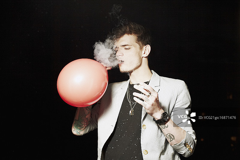 男人向气球里吹烟图片素材