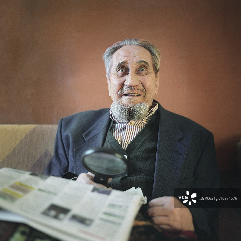 年长的男人用放大镜阅读报纸图片素材