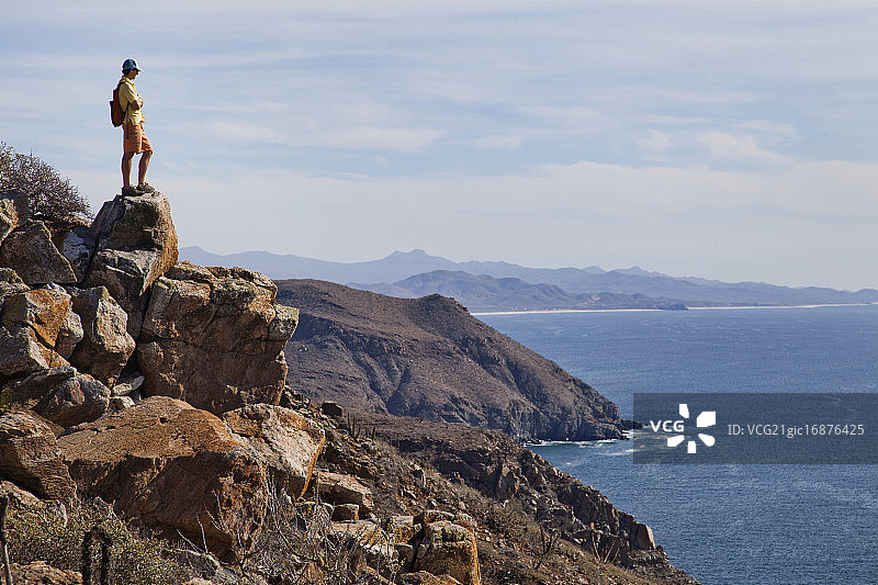 站在俯瞰太平洋的岩石突起边缘的年轻男人，佩斯卡德罗，美国加利福尼亚州图片素材