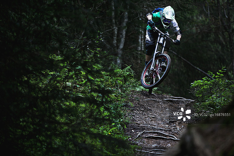 骑行者在小路上飞跃树根图片素材