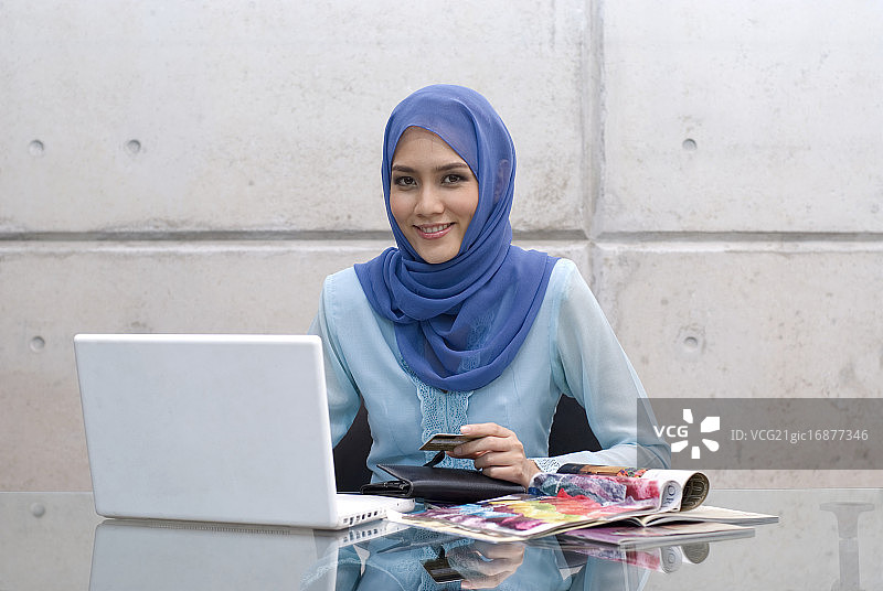 使用信用卡和笔记本电脑的马来西亚穆斯林妇女图片素材