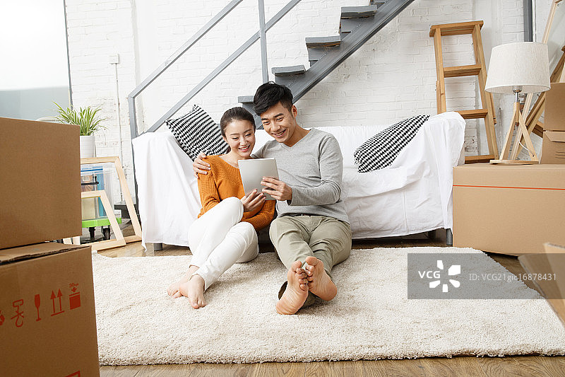 青年情侣坐在地毯上使用平板电脑图片素材