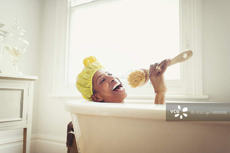 在浴缸里拿着丝瓜瓤刷唱歌的快乐中年妇女图片素材