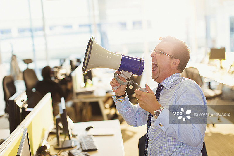 在办公室里用扩音器大喊大叫的商人图片素材