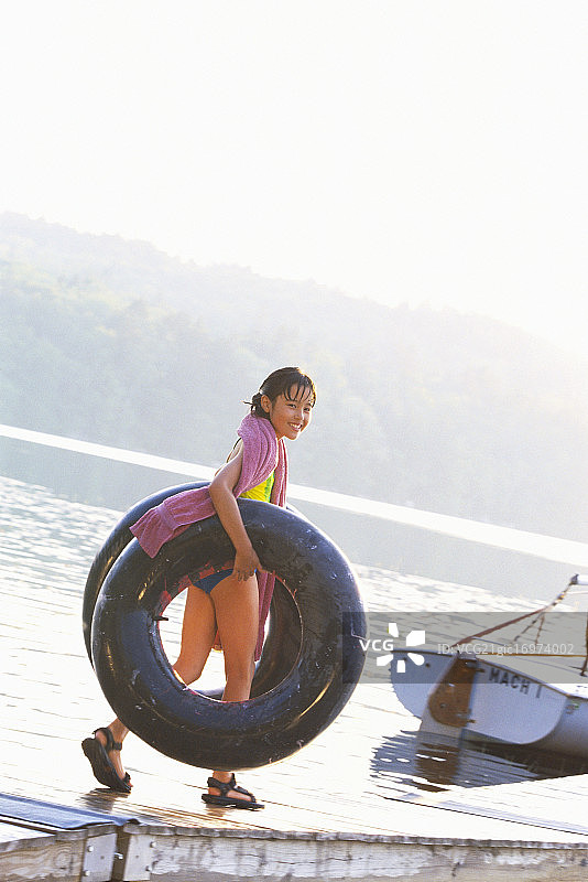 女孩拿着内胎走下码头图片素材