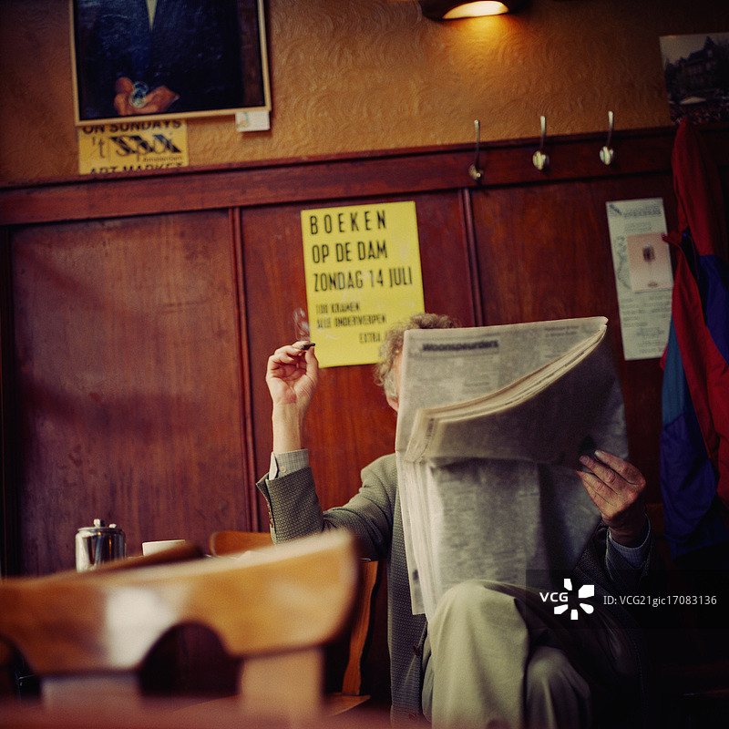 在咖啡馆阅读报纸时吸烟图片素材
