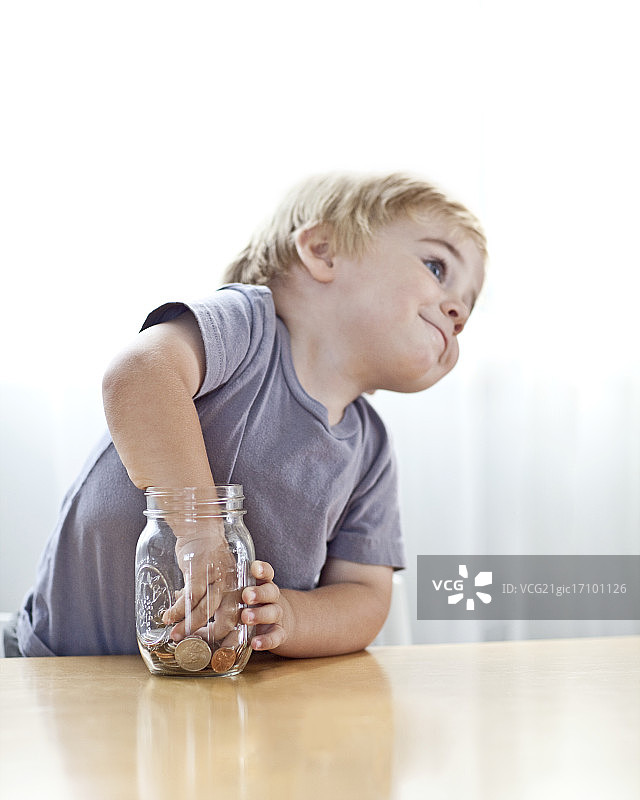 往梅森罐子里放东西的小男孩图片素材