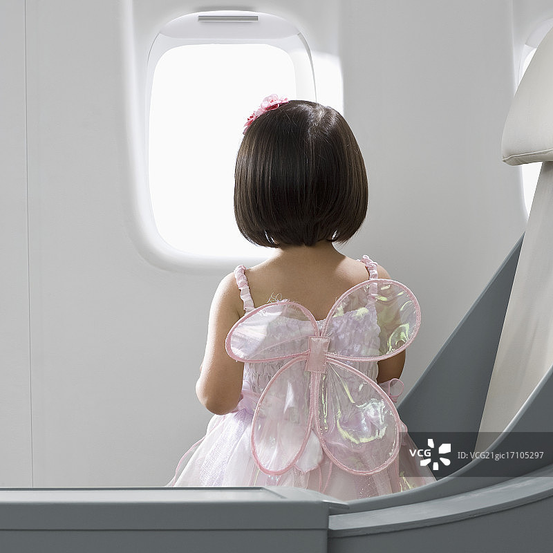 穿着仙女服装的女孩望着飞机窗外图片素材