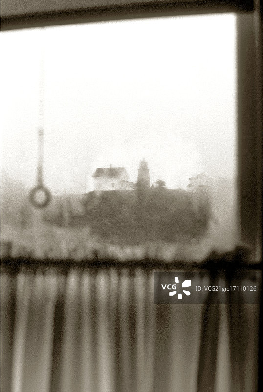 透过脏窗户看到的房屋和灯塔景色图片素材