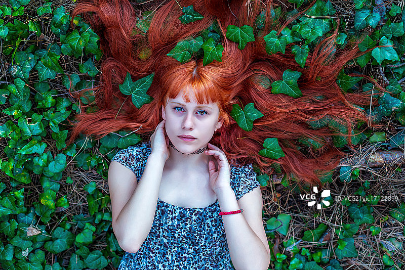 漂亮的红发女孩躺在常春藤中图片素材