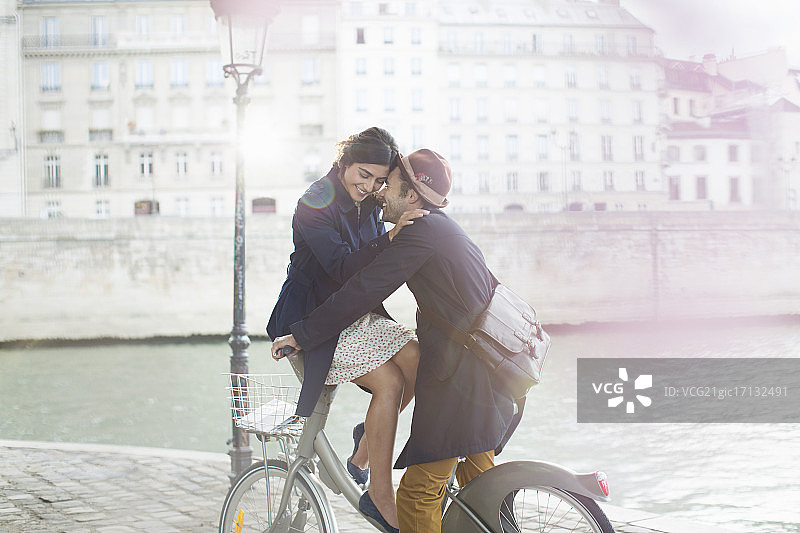 情侣在法国巴黎塞纳河畔骑自行车相拥图片素材