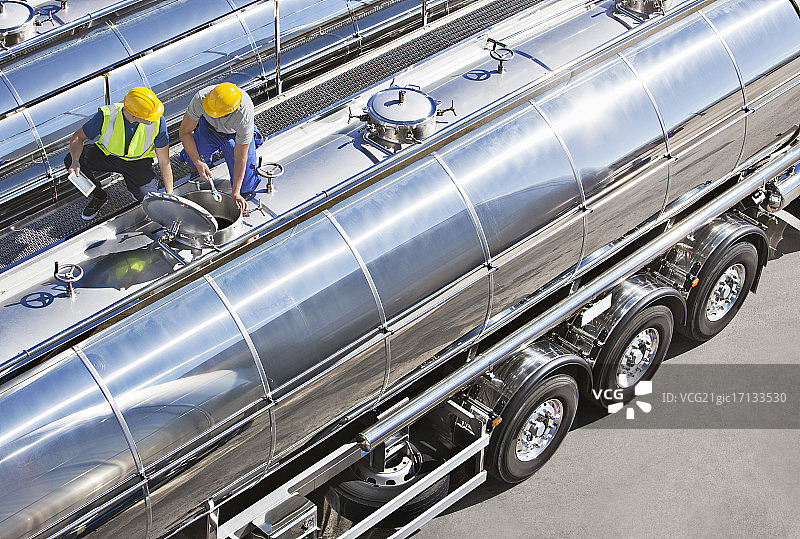 在不锈钢牛奶罐车顶部的工人图片素材