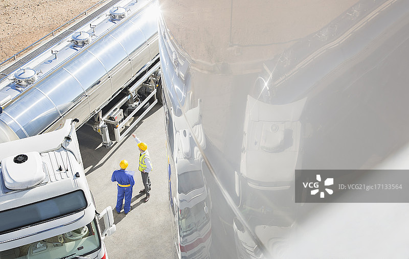 工人在不锈钢牛奶罐车旁交谈图片素材