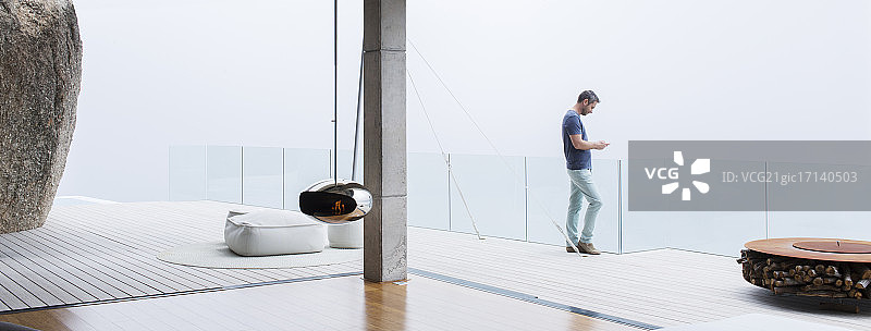 在现代住宅阳台上使用手机的男人图片素材