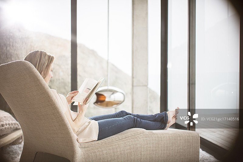在现代客厅沙发上看书的女人图片素材